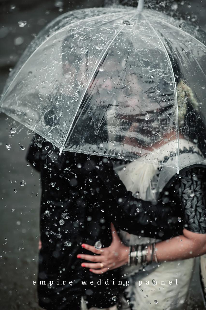 Wedding couple beneath a transparent umbrella in the rain
